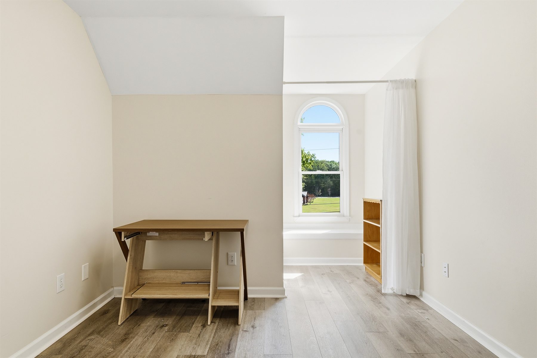 Additional upstairs bedroom with arched window and built-in shelf area