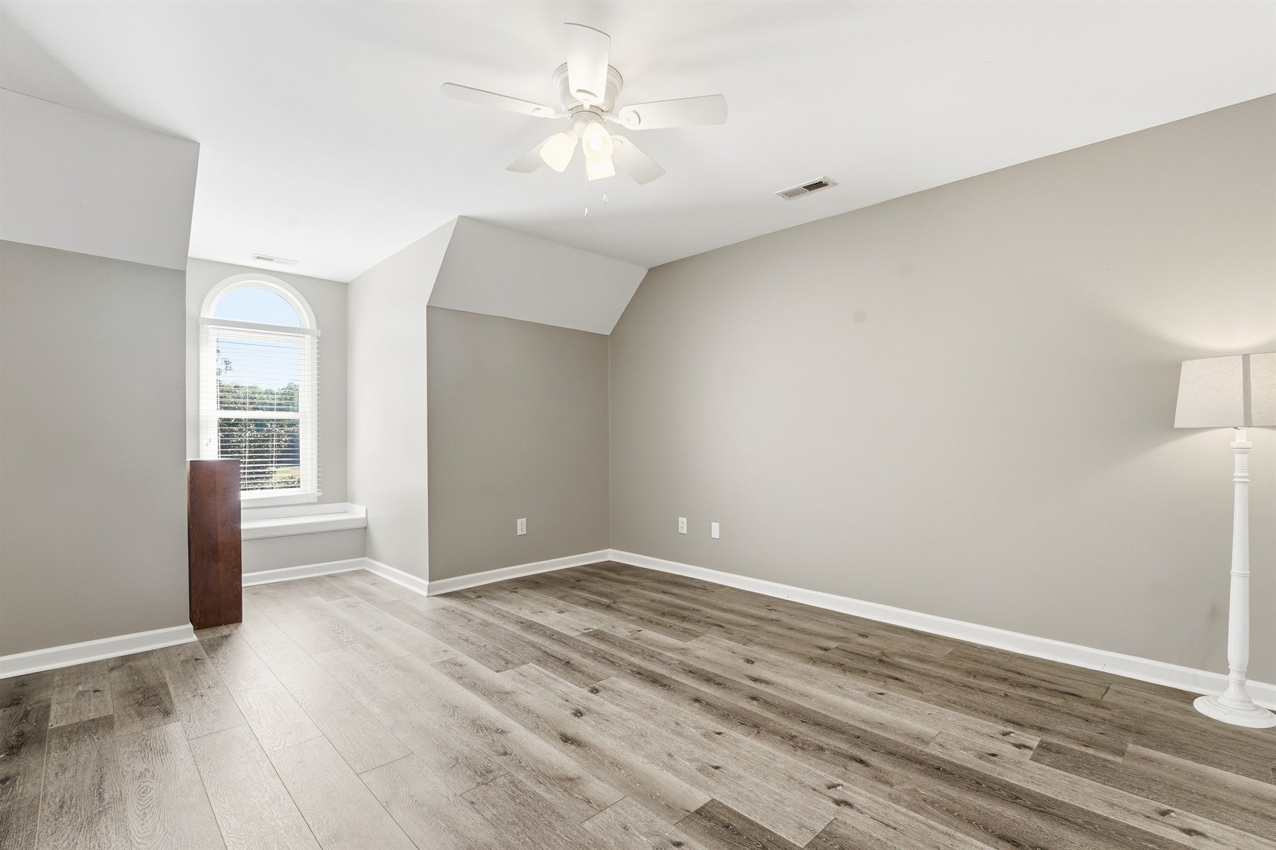 Upstairs bedroom with angled ceiling and arched window